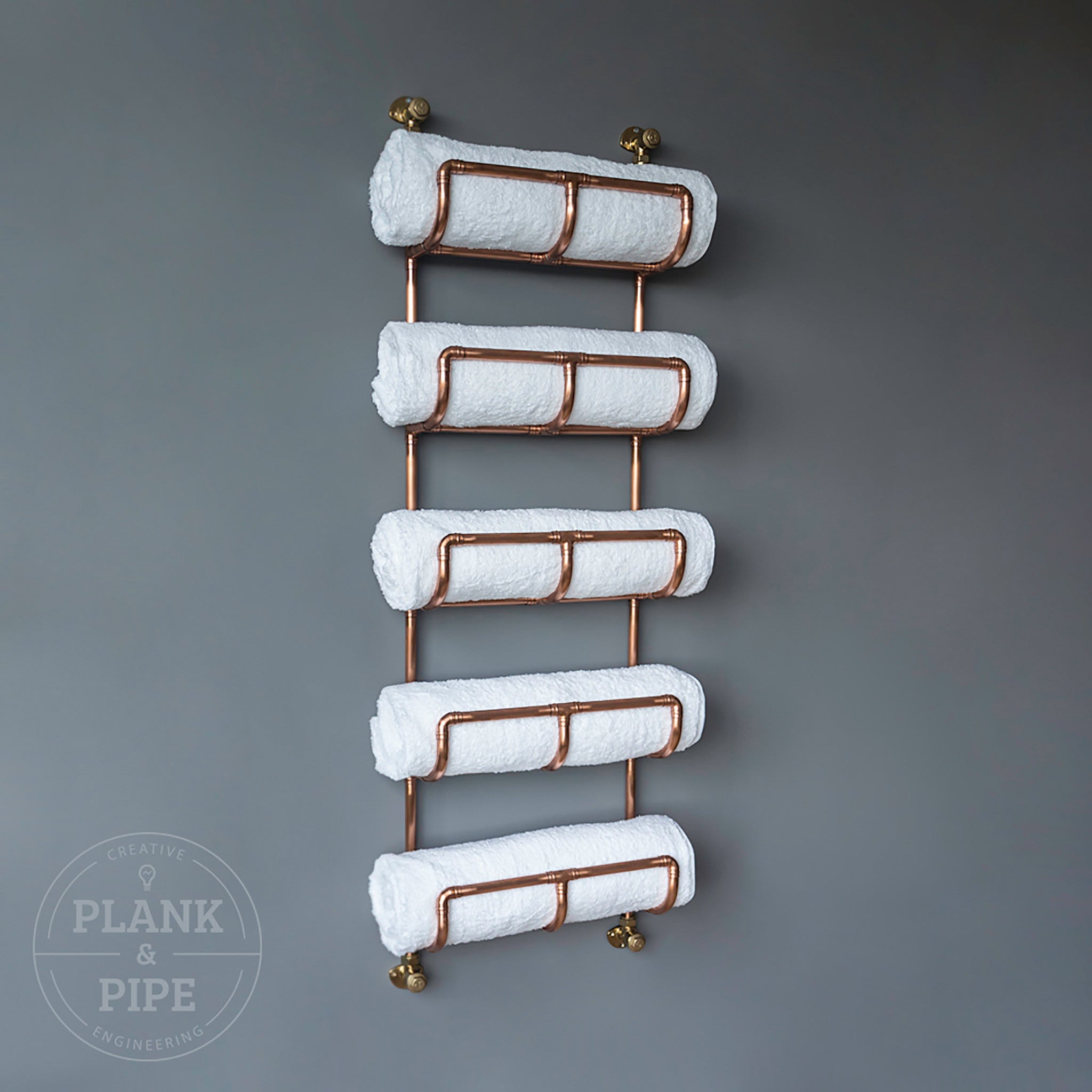 Copper towel rack holding 5 white towels